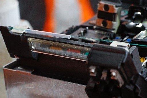 Gros plan sur un appareil de soudure de fibres optiques en cours d’utilisation.