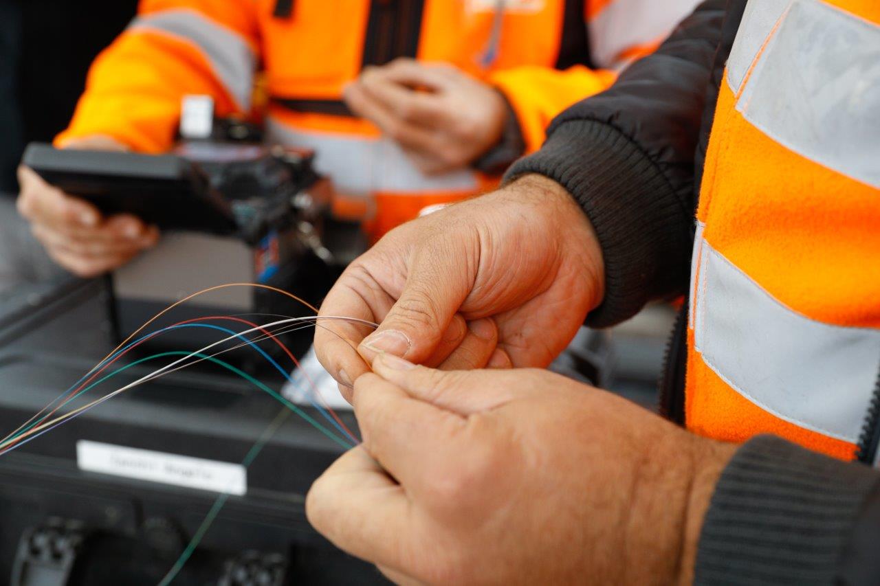 Technicien tenant des fibres optiques lors de travaux d’installation FTTH.